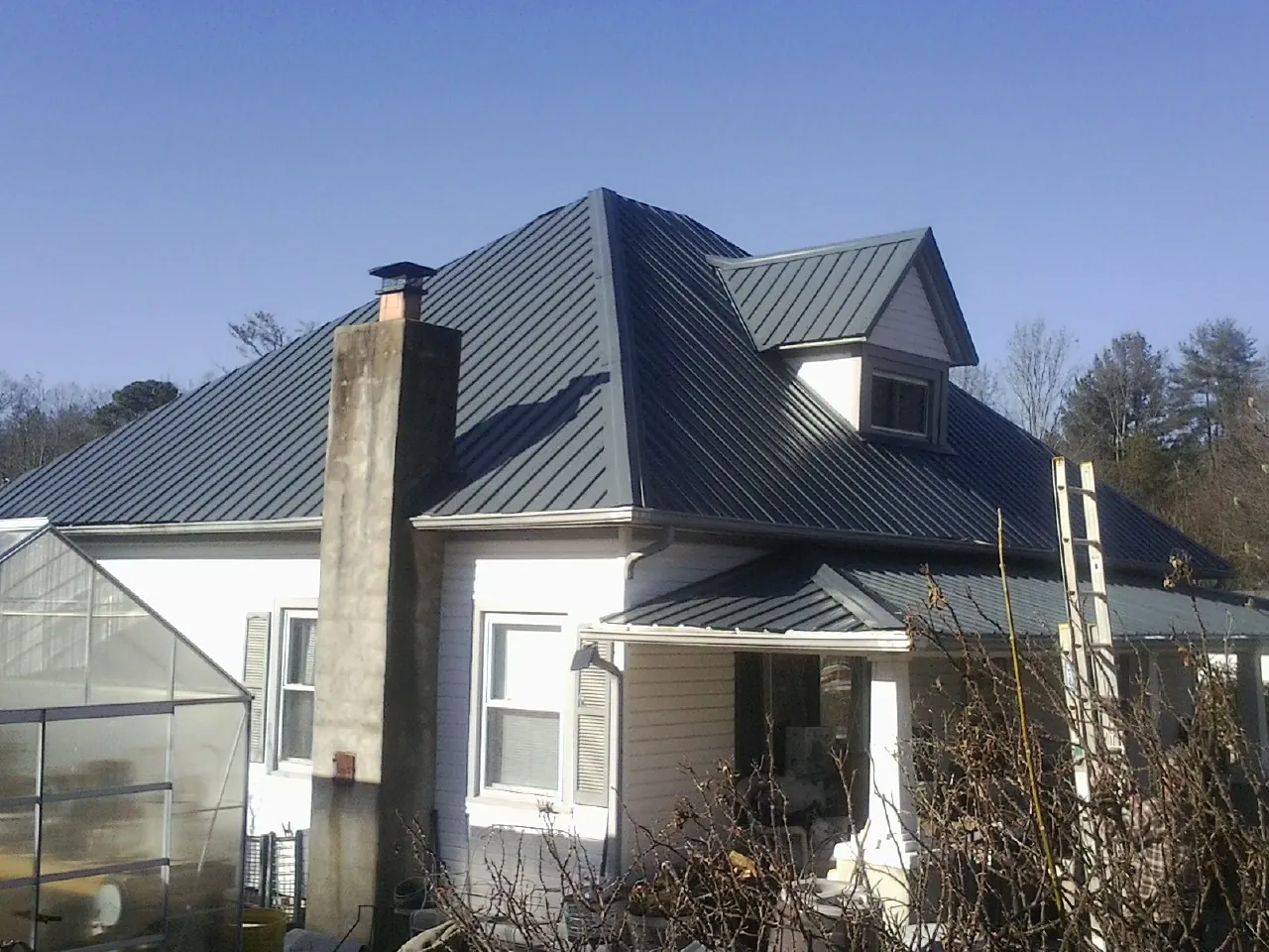Dark blue standing seam metal roof on a white farmhouse with dormer — Slate & Tile Roof Repair by Roofing Brothers in Pequannock