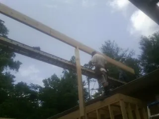 Carpenter setting a ridge beam over a new addition frame — Ice Dam Removal by Roofing Brothers in Pequannock