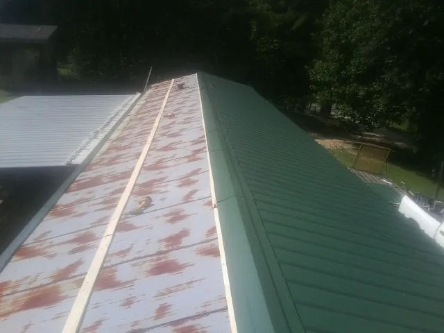 Old rusted panels beside newly installed green metal roofing — Wind Damage Roof Repair by Roofing Brothers in Pequannock