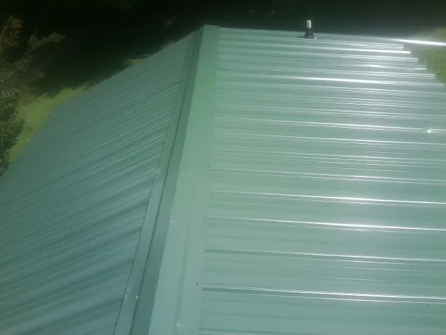 New green metal panels meeting at the ridge of a roof — Flat Roof Repair work by our crew in Pequannock