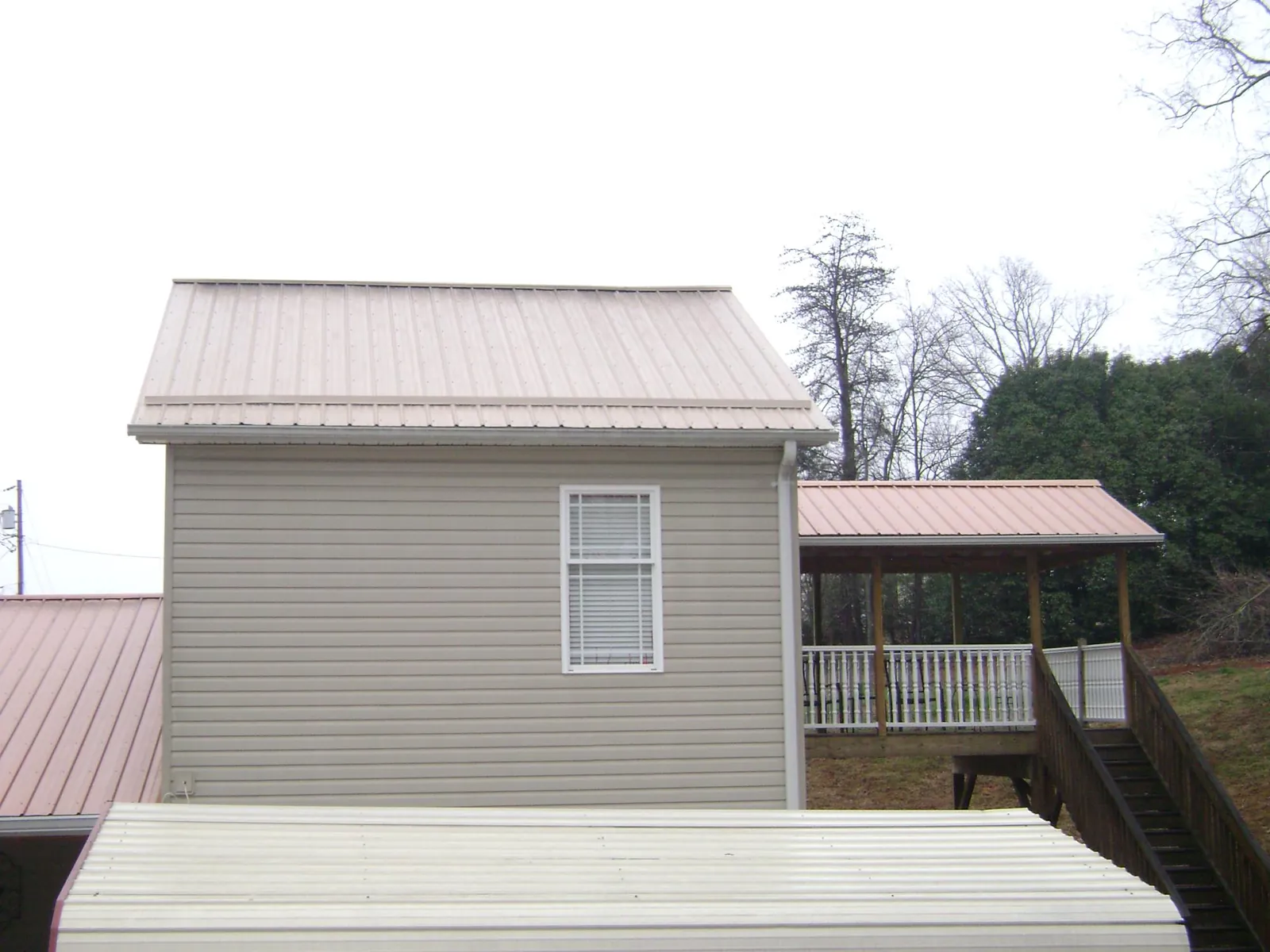 Tan metal roofs on a two story addition and attached porch, from a Roof Replacement job in Pequannock