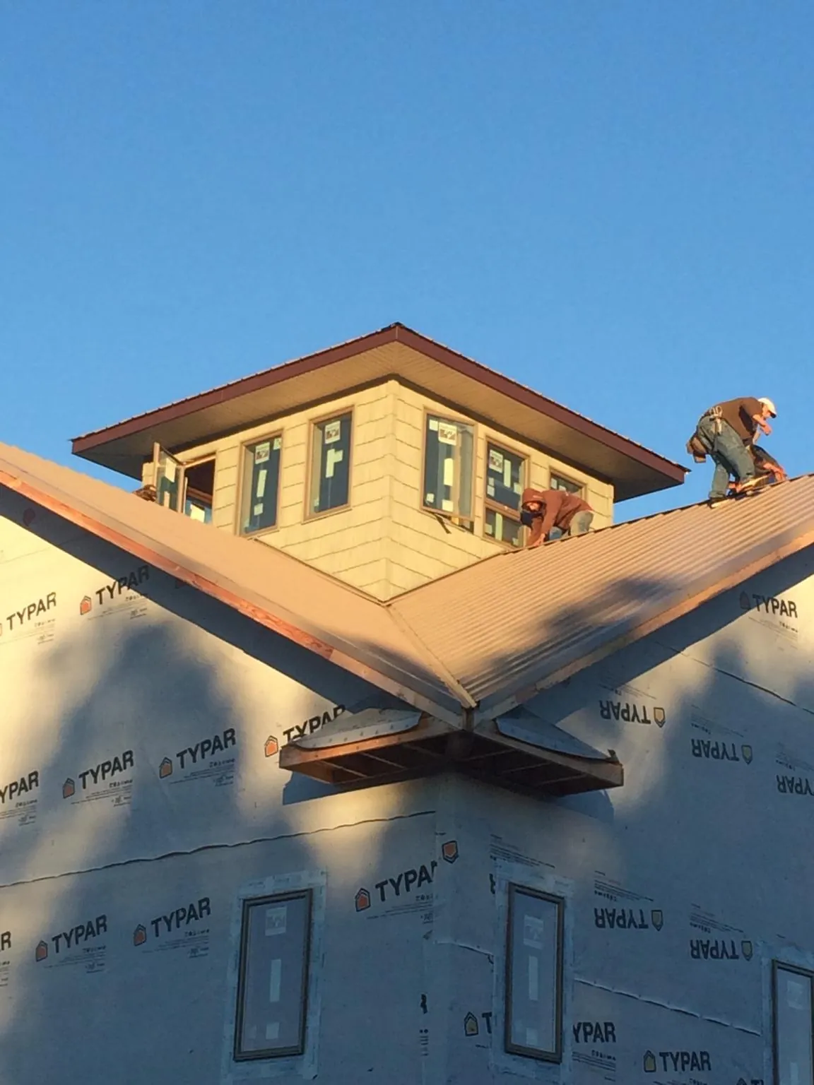 Roofers working around a rooftop cupola on a new metal roof at sunset — Roof Waterproofing in Pequannock by Roofing Brothers